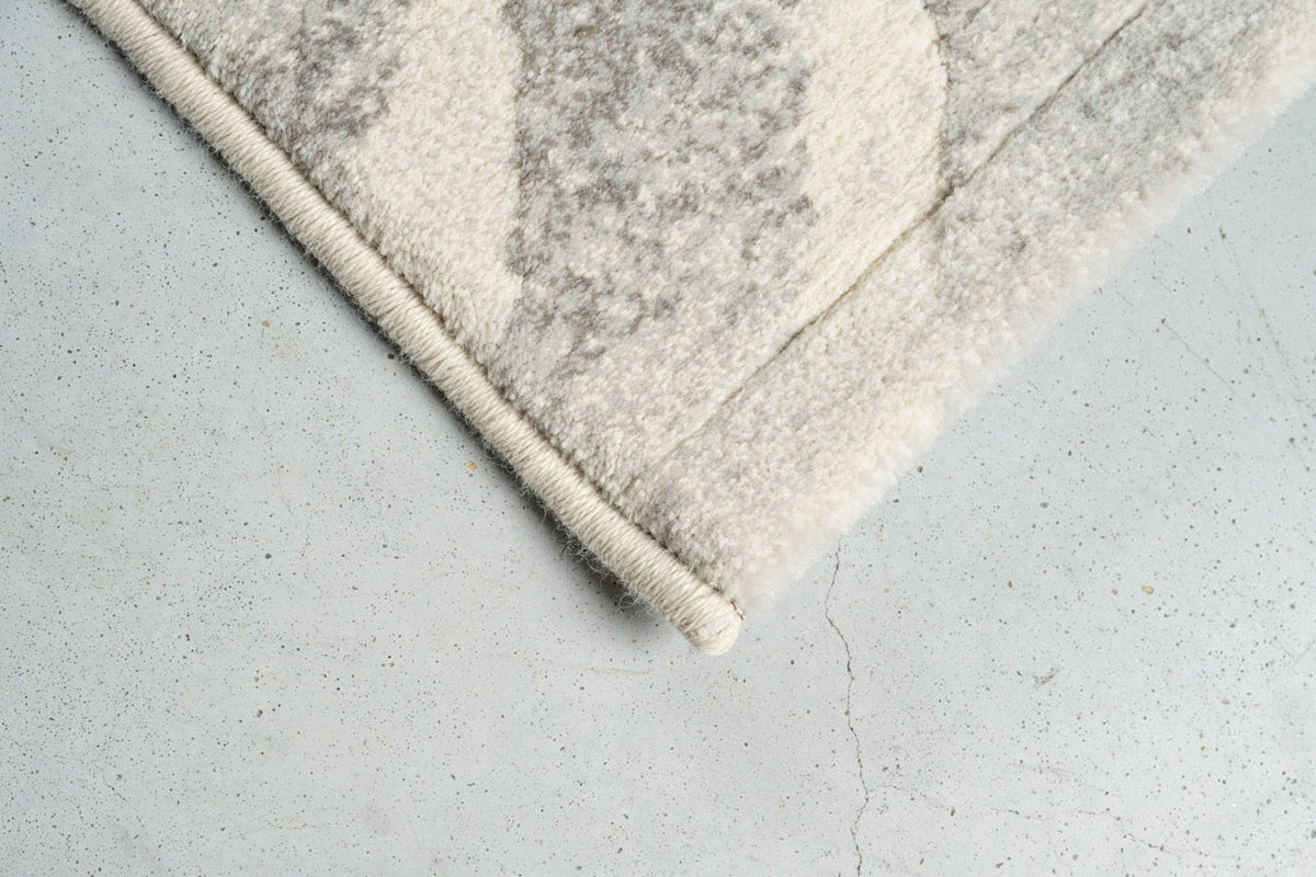 Eckdetail des Teppichs Tapison Home Torino 063.0990.6797 in Elfenbein und Hellgrau